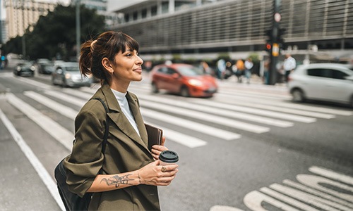 a person crossing the street holding a coffee
